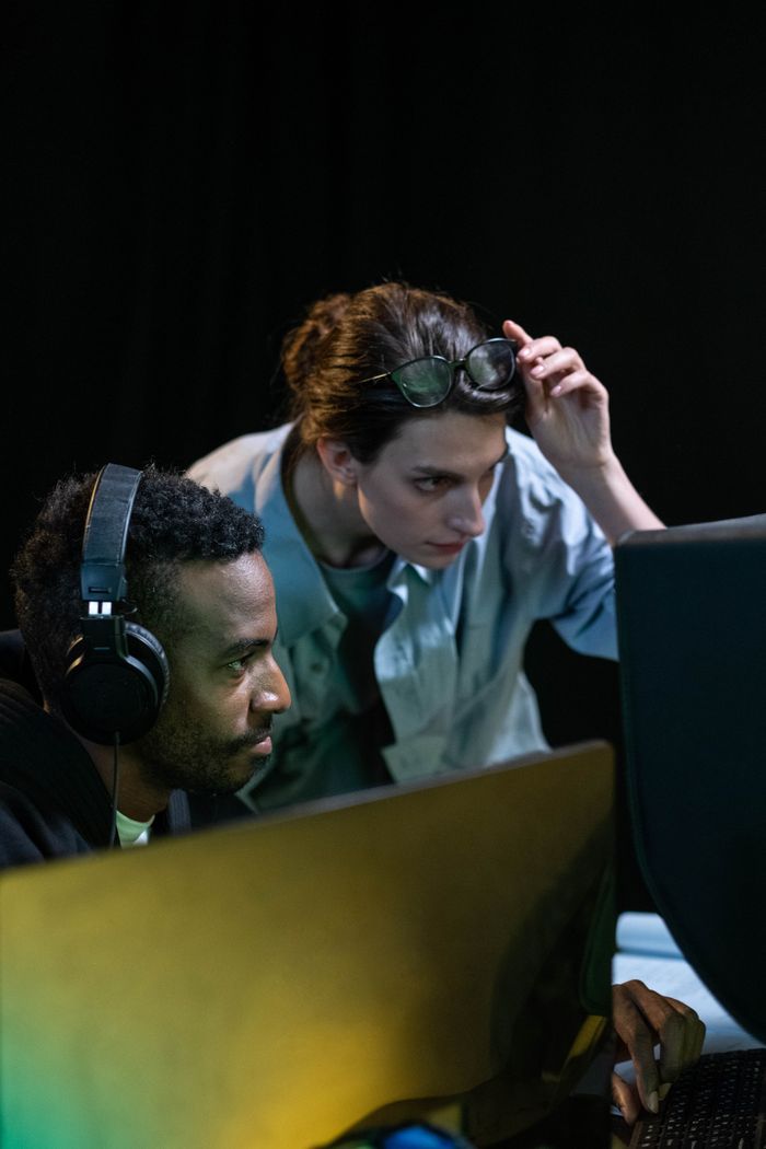 menu-01 Two colleagues focusing on a post production video editing task in a dark studio environment.